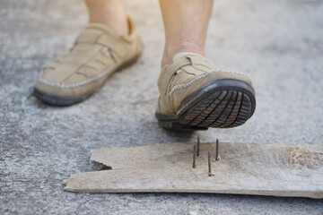 Closeup man wear shoes is stepping on rusty metal nail on wood. Concept, unsafe , risk for...