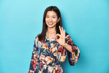 Elegant young Asian woman in kimono, studio shot cheerful and confident showing ok gesture.
