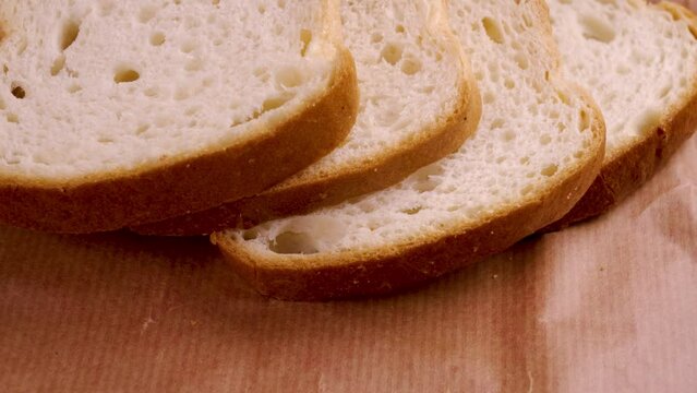 Sliced loaf of fresh white bread on wrapping paper closeup