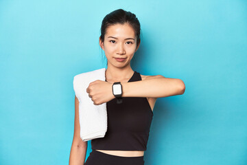 Fototapeta na wymiar Sportswoman showing smartwatch feature, studio backdrop.