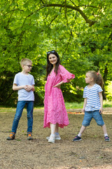 Fototapeta premium A mother and two school-age children, a boy and a girl, in nature.