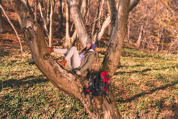 Woman relaxing in the tree while spending autumn day in the forest