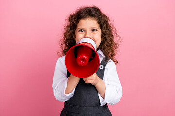 Portrait of positive small schoolkid hands hold loudspeaker toa communicate isolated on pink color...