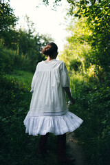 Beautiful young Indian woman smelling flower in the park, wearing white dress