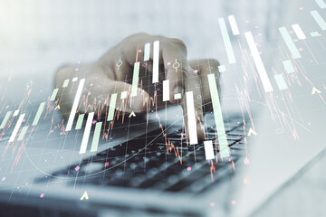 Multi exposure of abstract creative financial graph with hand typing on laptop on background, forex and investment concept