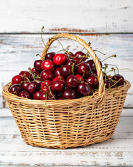 Fresh cherry in a wicker basket over wooden background. Cherry harvest season concept. Healthy and fresh fruit. Close up