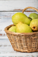 Fresh pears in a wicker basket over wooden background. Pear harvest season concept. Healthy and fresh fruit. Close up