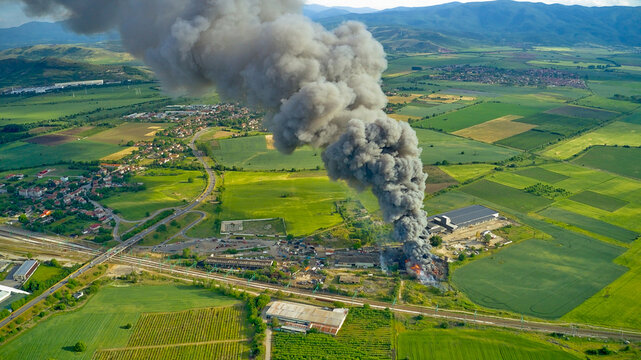 A black column of smoke and a fire in a warehouse, against the backdrop of the city. Photo from above from a drone.
