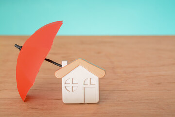 Red umbrella and toy house with copy space. Home protection and safety assurance concept