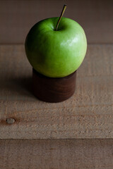 Ripe granny smith apple on wooden dowel.