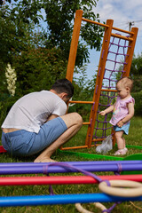 Fototapeta premium Dad with little daughter collects home sports complex outdoor.