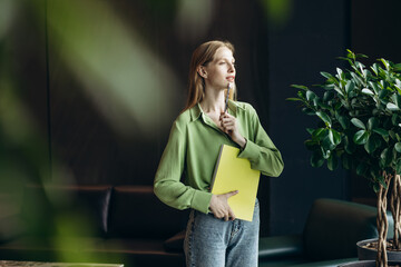 Business woman standing with book by the window