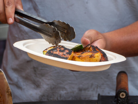 Plating Grilled Potatoes and Vegetables with Tongs on a Paper Plate
