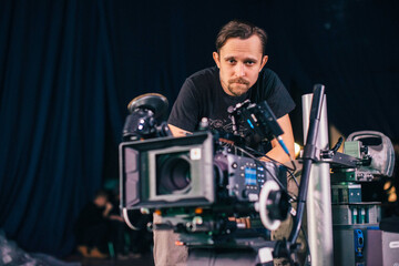 Director of photography with a camera in his hands on the set. Professional videographer at work on filming a movie, commercial or TV series.