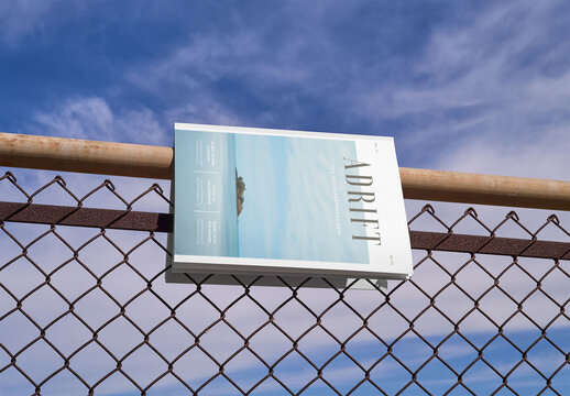 Mockup of vertical A4 magazine with customizable front cover hanging on top of wire fence