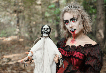 A woman in the form of a vampire or a witch holds a doll in the form of death in her hands. Blood...
