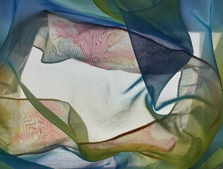 Text space surrounded with backlit colorful translucent fabrics in blue, red, green. Soft curves show dimension and ethereal effect. Dreamy look with screen texture background.