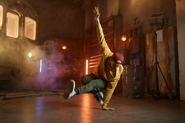Handsome young man dancing movements over urban studio background