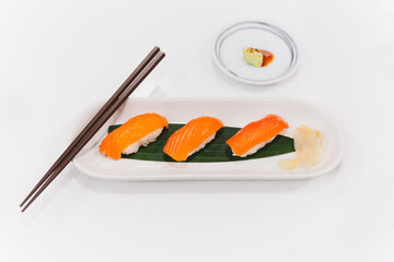 Salmon shushi roll and wasabi shoyu sauce with chopsticks.