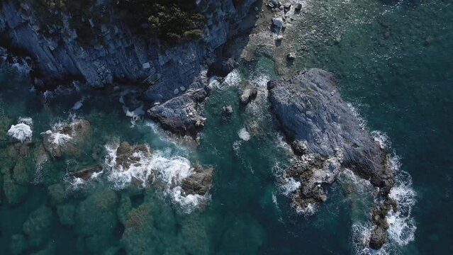 Drone 4k top down view of a beach shore with rocks and waves seamless loop Greece