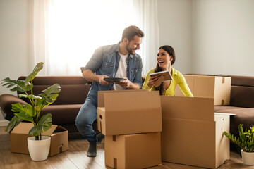 Smiling couple unpaking boxes in new home - 626979340