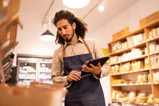 Serious man with tablet checking goods in grocery store