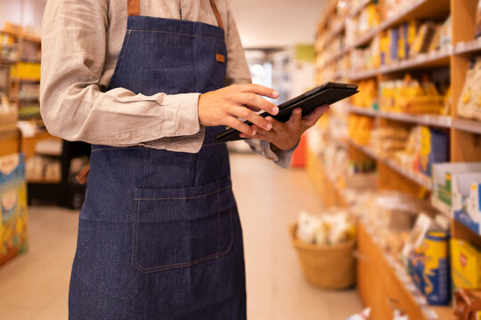 Anonymous man with tablet checking goods in grocery store