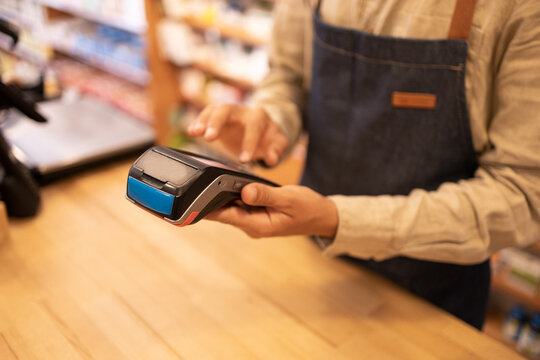 Crop unrecognizable man using point of sale machine in shop