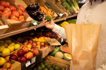 Crop man choosing fruit in fruit shop