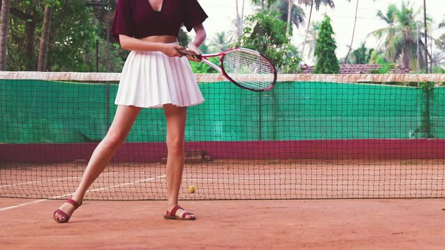 young woman in a white skirt hits the tennis ball with her racket