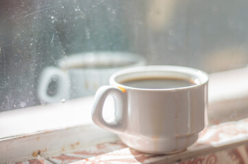 Fototapeta premium Coffee cup with reflection in the glass,the glass is dirty purposely,simple living concept