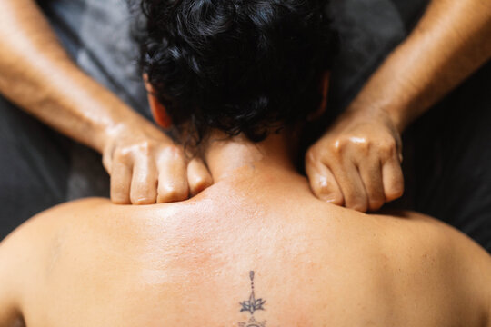 Unrecognizable masseur doing deep tissue massage on shoulders of anonymous client
