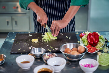 Chef is cutting vegetable on table in realistic kitchen for cooking menu.