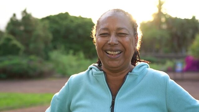 Senior african woman smiling in front of camera during sunset time at park 