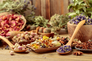 Various dried medicinal plants, herbs, and flowers on an old wooden background.