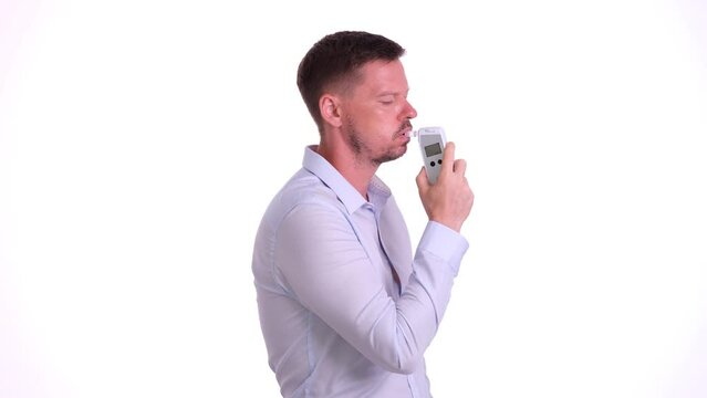 Man blows into breathalyzer on white background. Breathalyzer test and usage rules