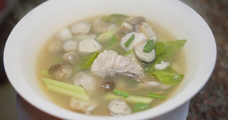 Close up Thai hot and spicy food tom yum Clear Soup with seafood and ingredients in bowl with smoke , famous Thai food Tom Yum Clear Soup is popular Thai cuisine