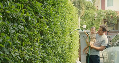 happy Asian family little cute adorable baby child daughter girl with his father watering plants in...