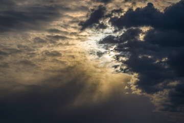 Naklejka premium Dark ominous clouds at bright sunset, sun beams
