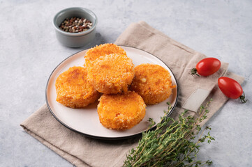 Fried vegetarian cutlets from carrot, on a plate on a light background with fresh herbs and tomatoes. Delicious homemade vegan diet food