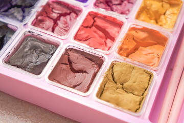 Dried colorful gouache in pink painting palette box. Cracked water color.