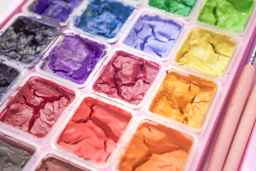 Dried colorful gouache in pink painting palette box. Cracked water color.