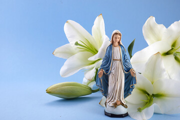 Assumption of Mary day. Virgin Mary figurine with lily flowers. - obrazy, fototapety, plakaty