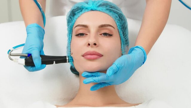 Perfect cleansing. Face of a beautiful pleasant woman being cleansed during hydrafacial procedure. Cosmetologist doing hydrafacial treatment on woman face in beauty clinic