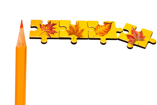 orange pencil with various pieces of puzzle with autumn leaves like creative artistic romantic autumn background with copy space 
