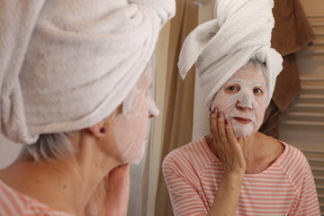 Senior woman moisturizing her face with collagen mask 