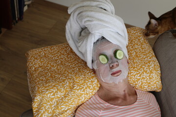 A healthy senior woman in her sixties is using cucumber during her skincare routine