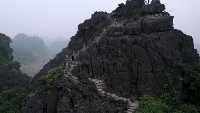 Vue a&eacute;rienne de Hang Mua &agrave; Ninh Binh au Vietnam, paysage karstique avec grotte, escalier et pagode sur la montagne du dragon couch&eacute;, culture et nature dans la baie d&rsquo;Halong terrestre.