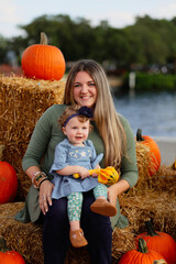 Happy Halloween and Thanksgiving - smiling mom and little daughter  on the background of orange pumpkins on holiday