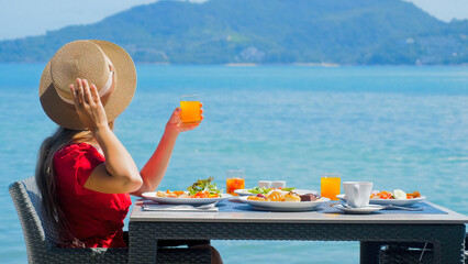 Young woman on vacation relishes her morning breakfast at a luxury resort restaurant with a...